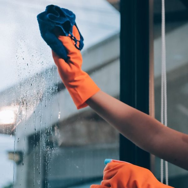 Young female worker cleaning window glass with cloth in spacious villa Young female worker cleaning window glass with cloth in spacious villa
